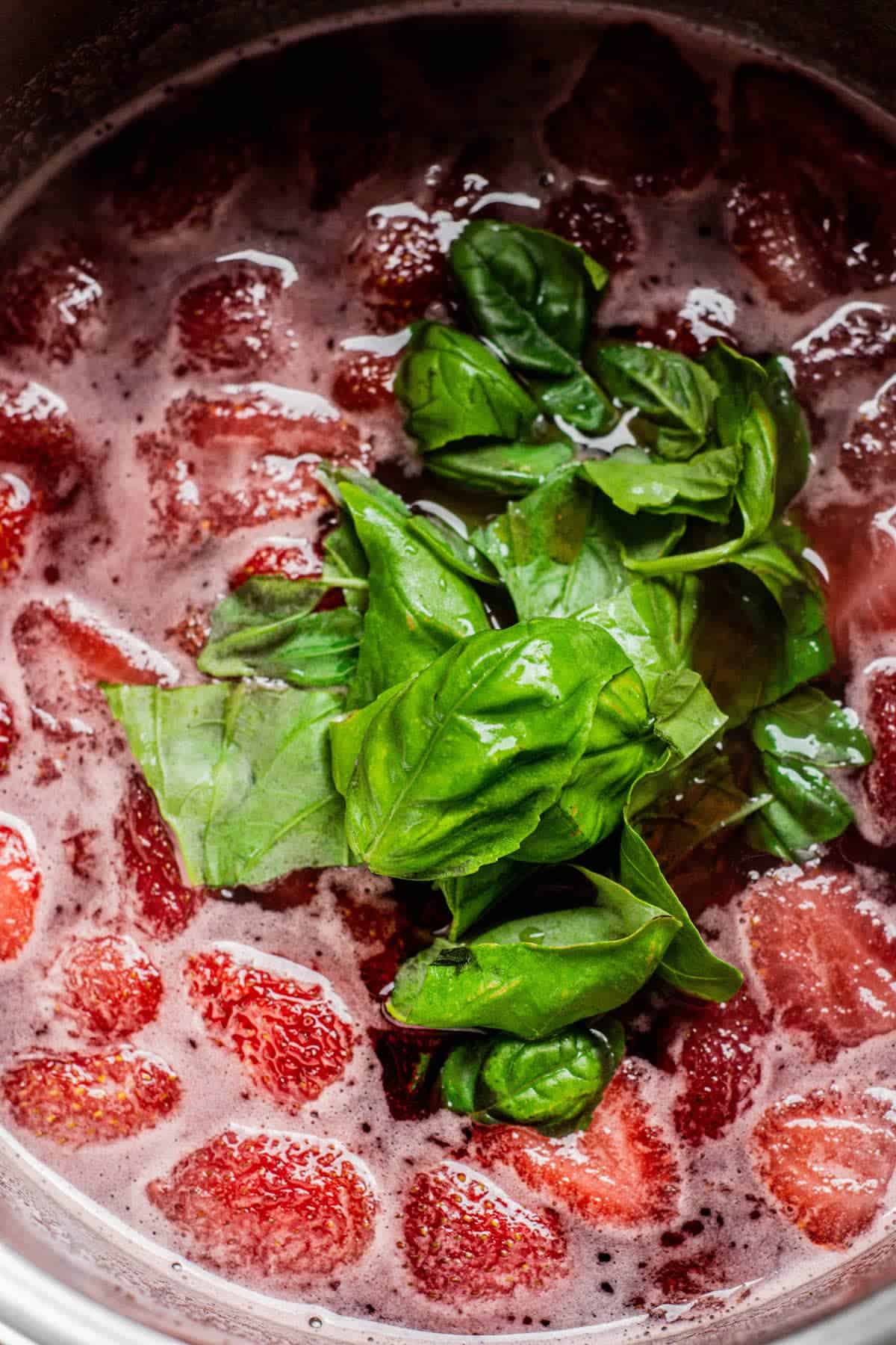 torn basil leaves in strawberry syrup.