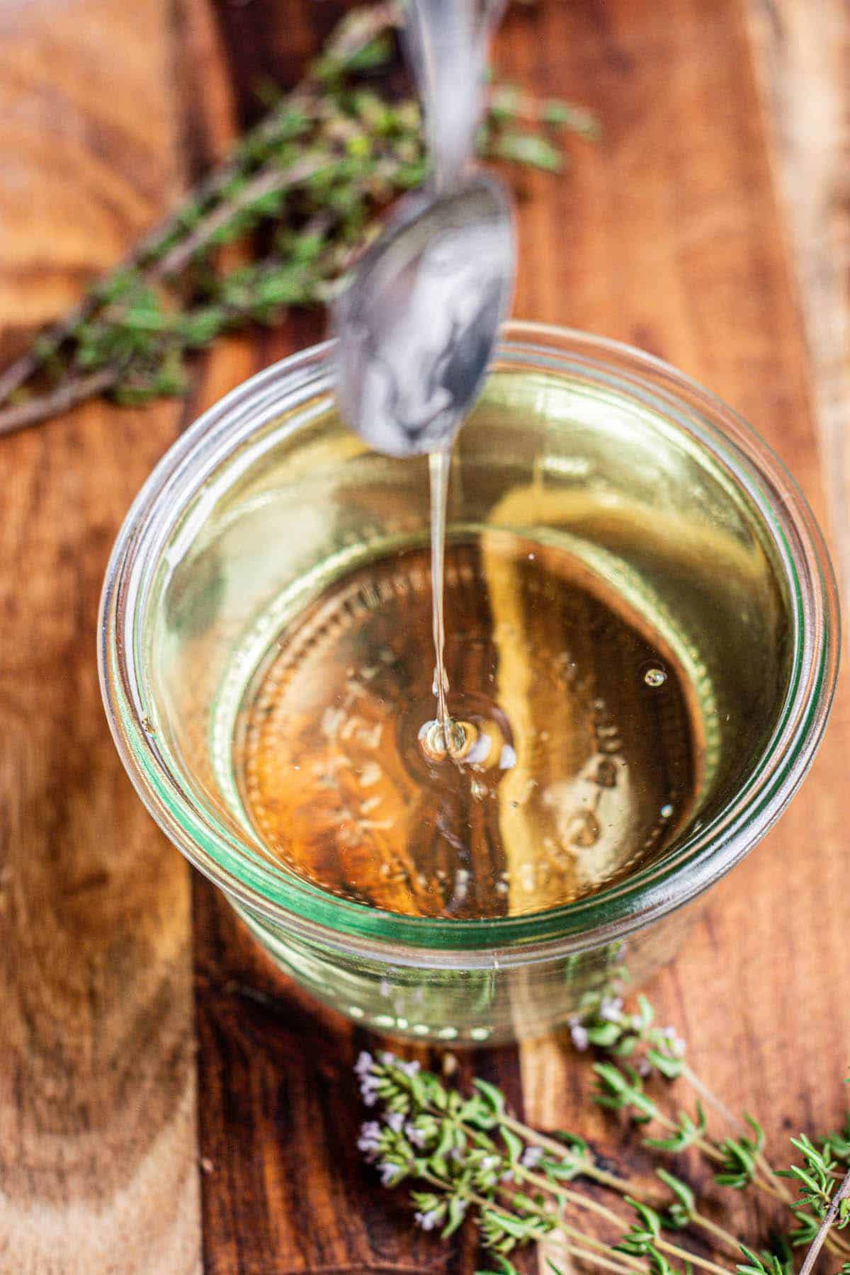 a spoon drizzling syrup with thyme.