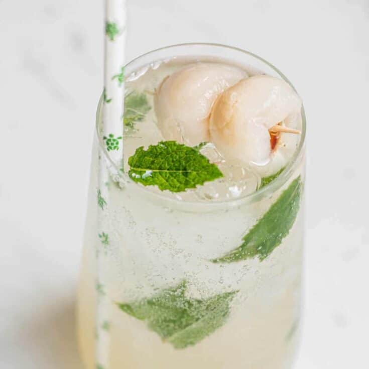 lychee mojito in a tall glass with mint and straw with little green turtles on it.
