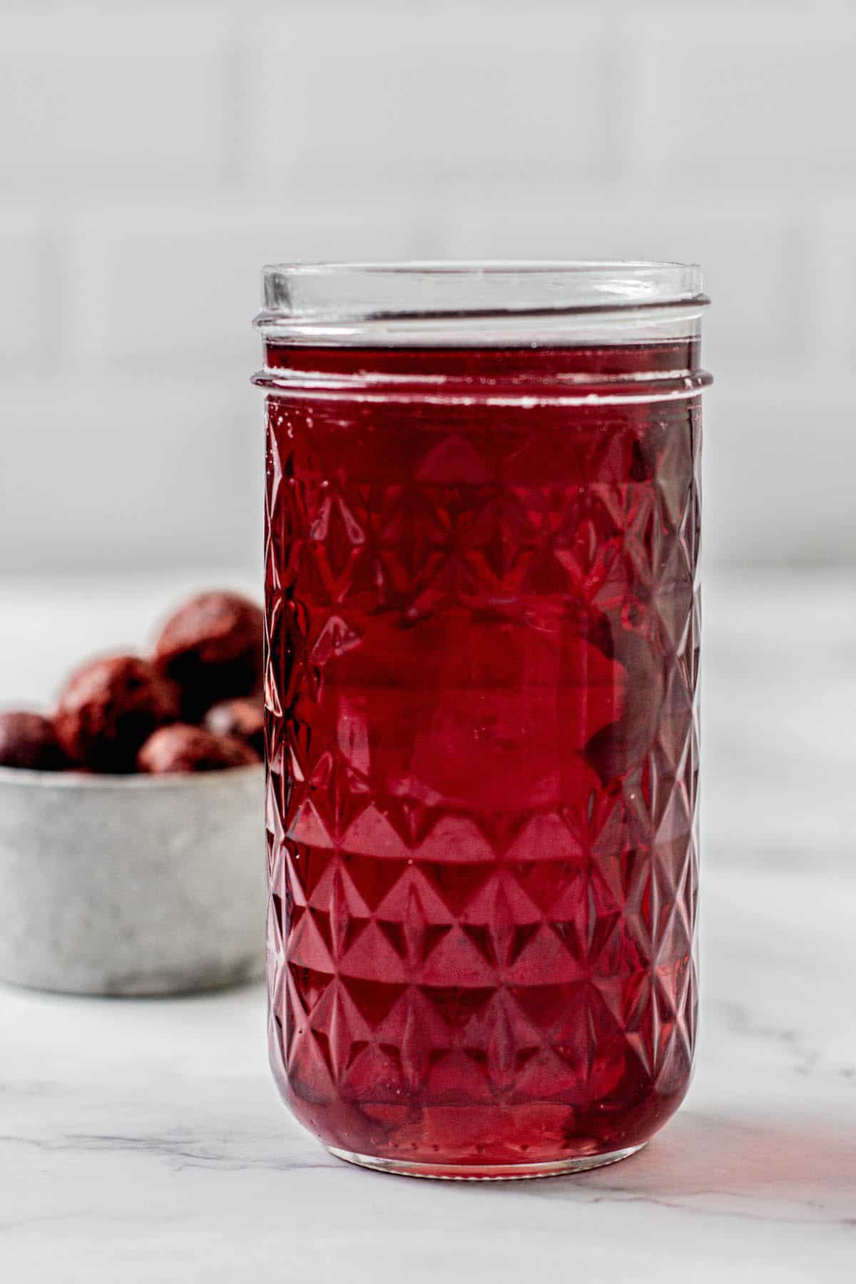 a glass jar of cherry simple syrup.