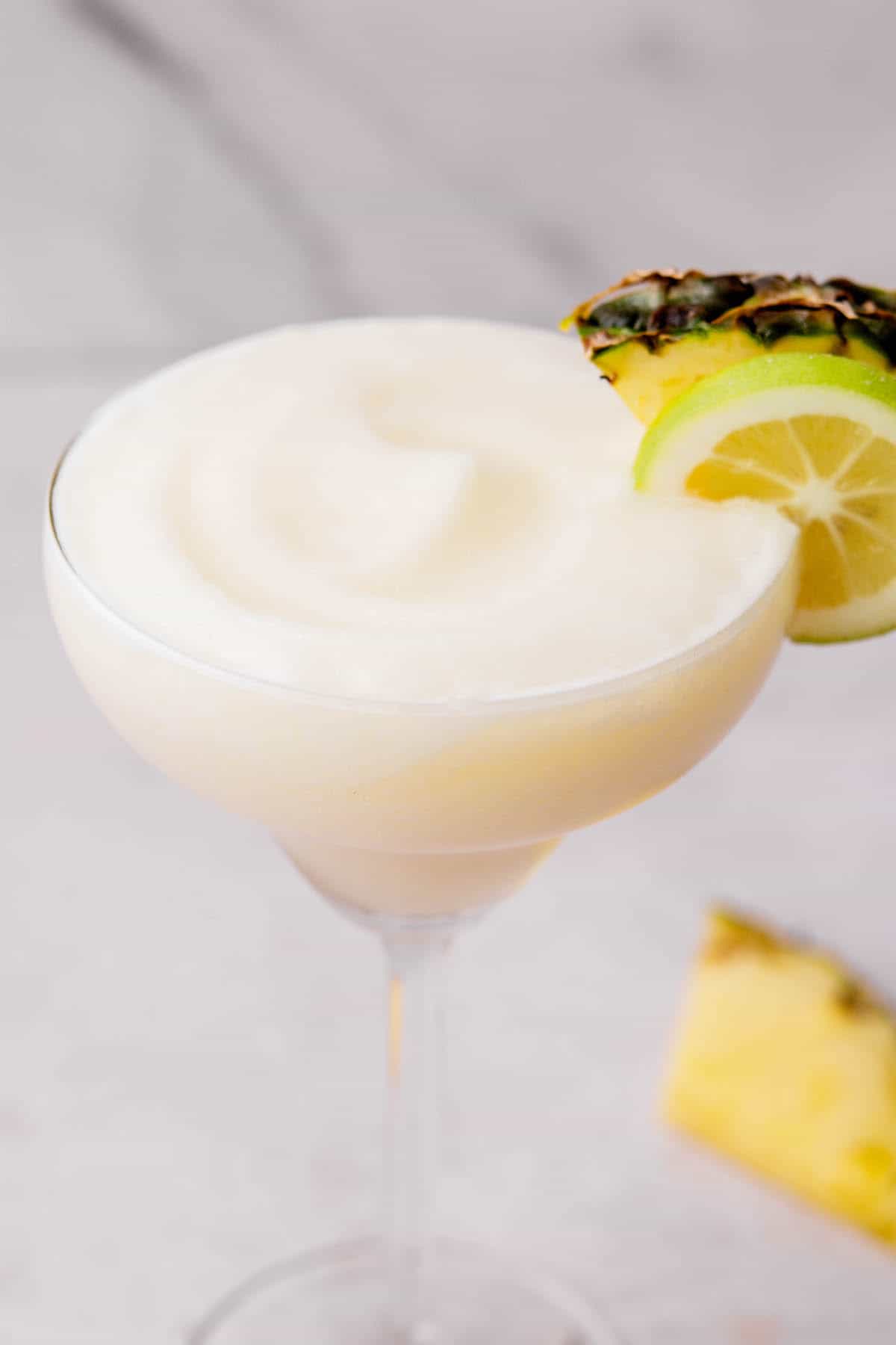 close up of a pina colada with tequila and pineapple wedge as garnish.