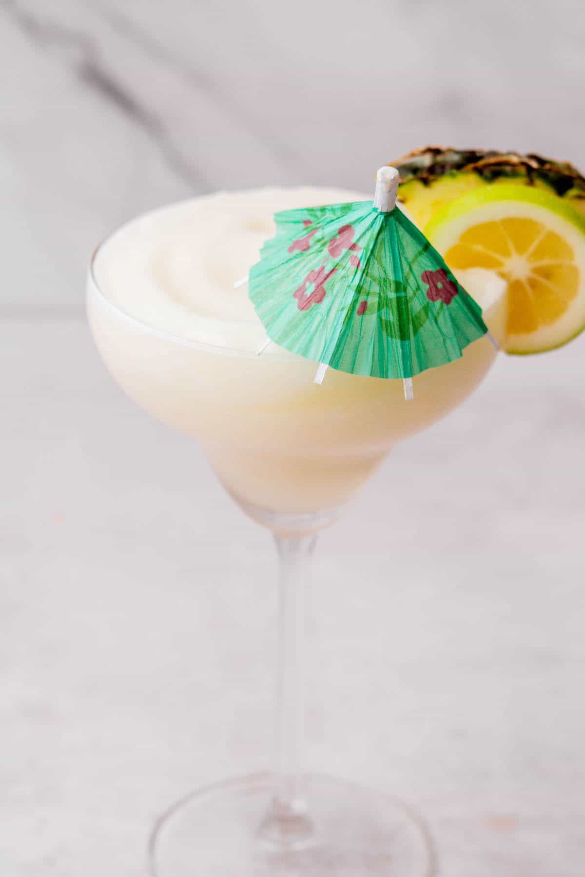 white pina colada with tequila with a cocktail umbrella, in a margarita glass.