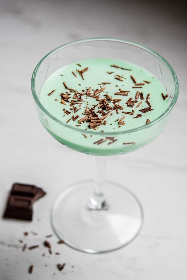 grasshopper cocktail in a coupe glass with a piece of chocolate next to it