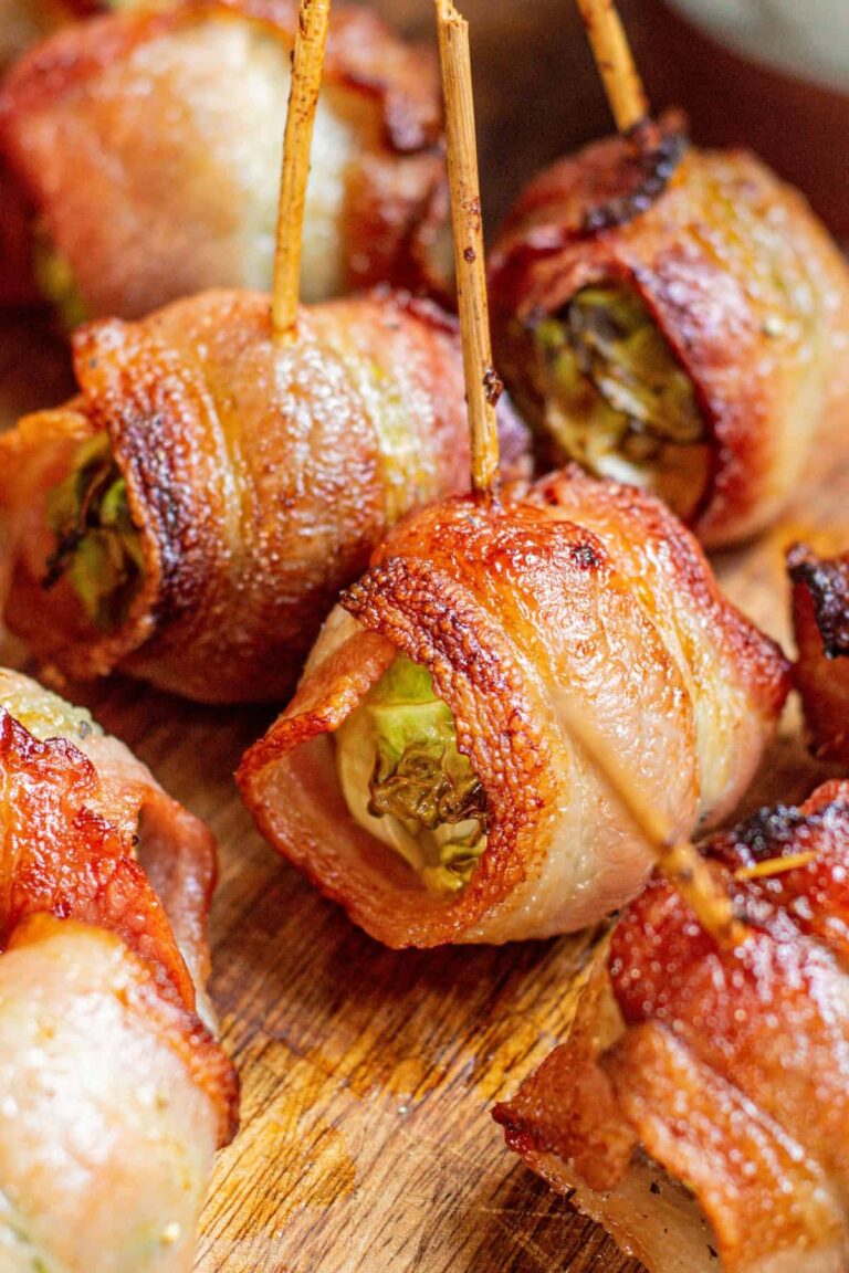 Crispy air fryer bacon-wrapped Brussels sprouts on a wooden board, each secured with a wooden toothpick, showing golden-brown, roasted edges and juicy centers.
